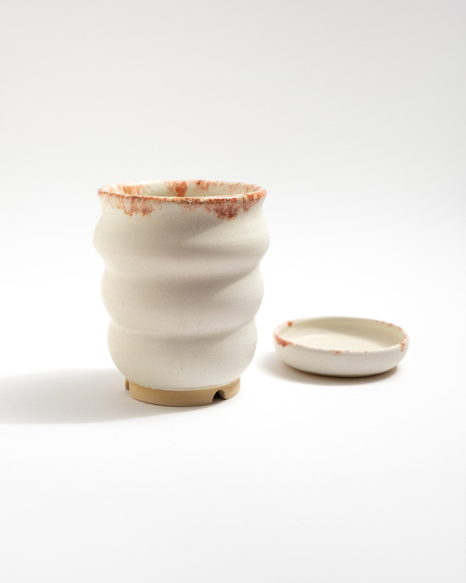 Handmade white stoneware planter with rust-red rim texture and raised foot for drainage
