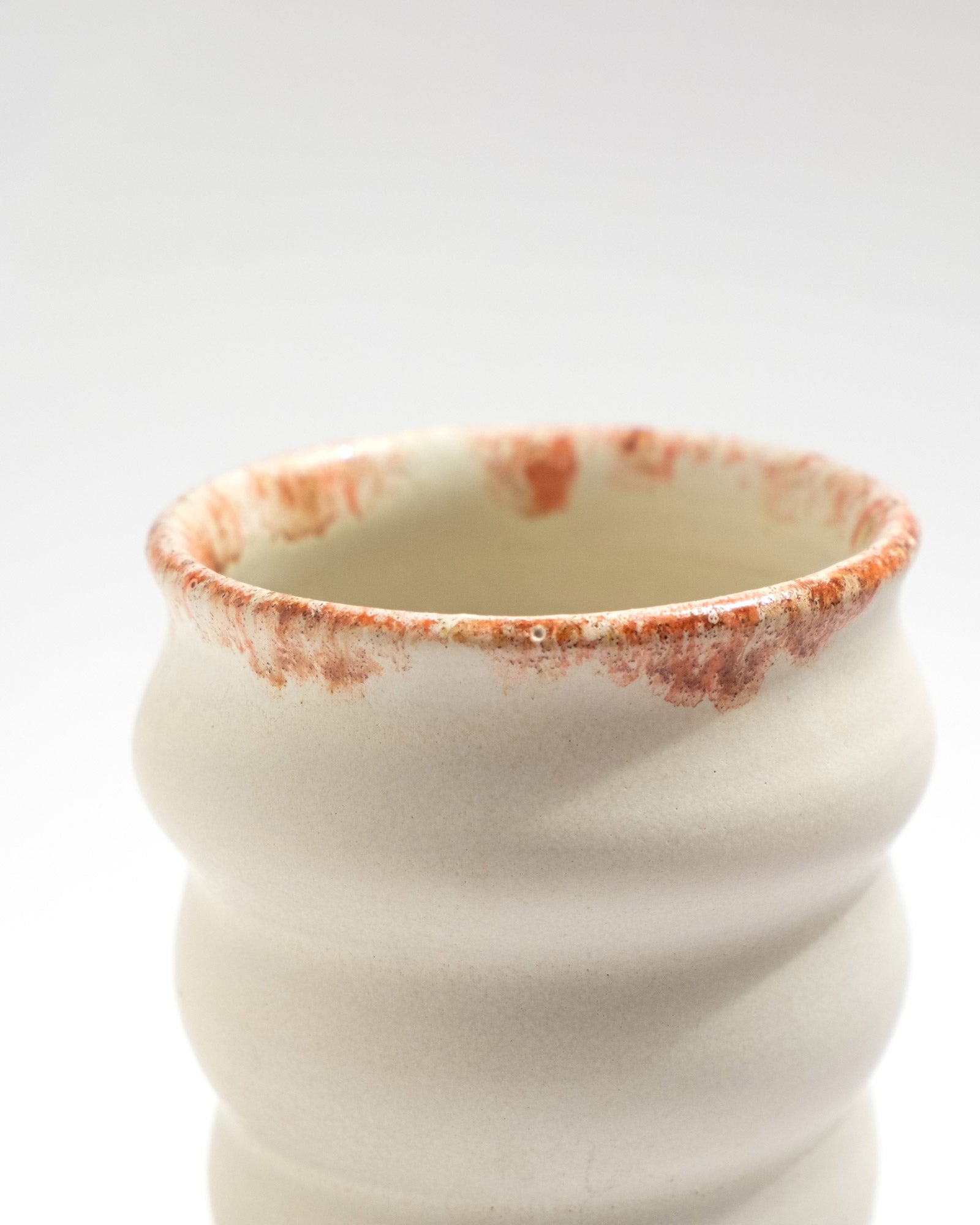 Handmade white stoneware planter with rust-red rim texture and raised foot for drainage
