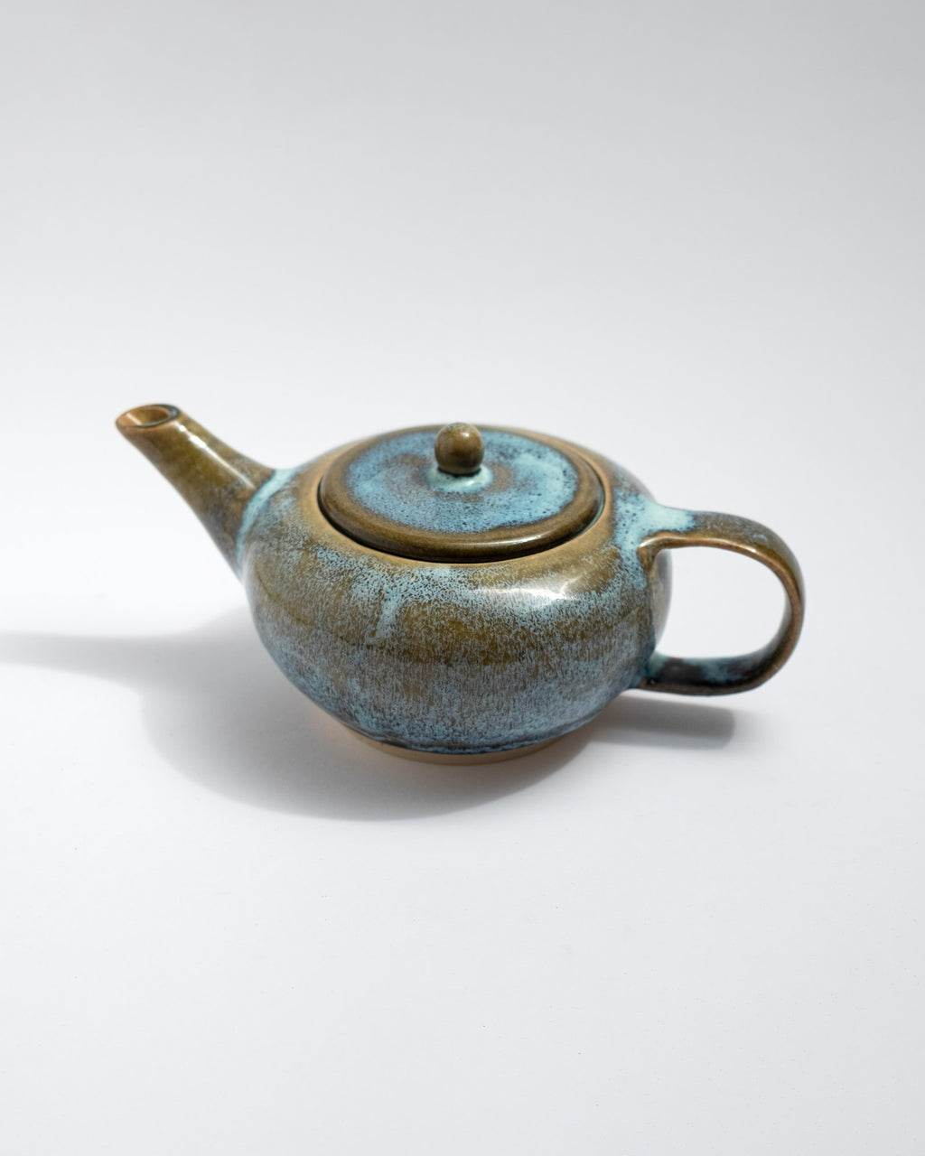 Handmade blue and brown stoneware teapot with flowing glaze and rounded body