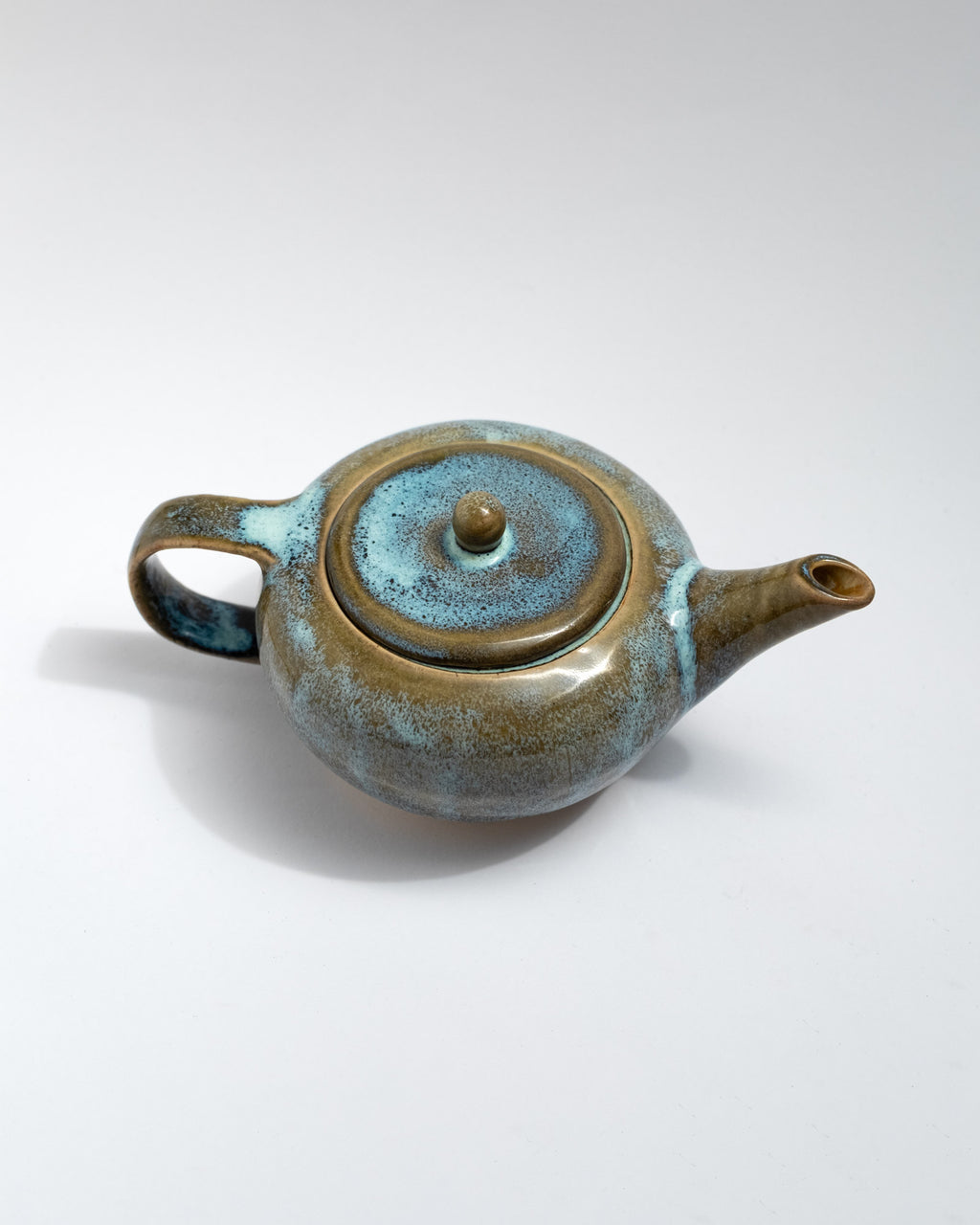 Handmade blue and brown stoneware teapot with flowing glaze and rounded body