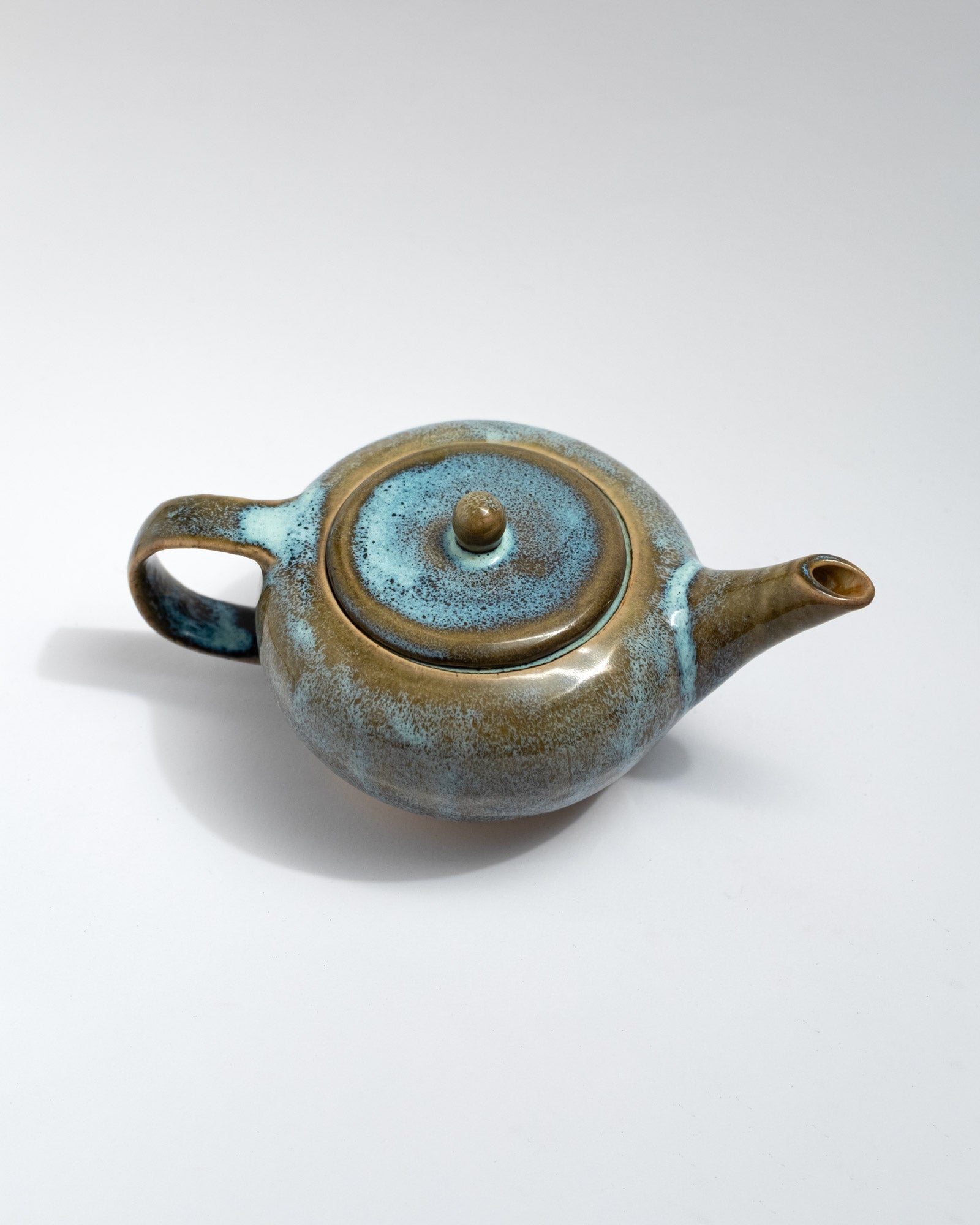 Handmade blue and brown stoneware teapot with flowing glaze and rounded body