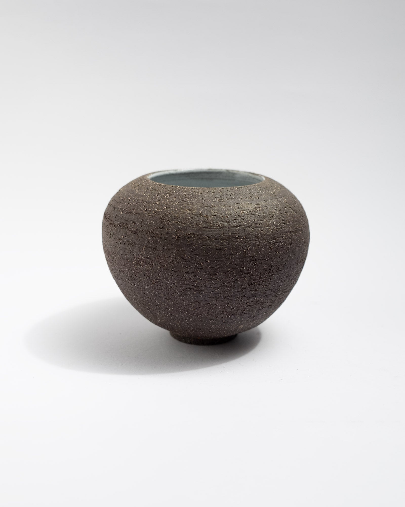 Handmade black clay vase with unglazed exterior and glossy white interior
