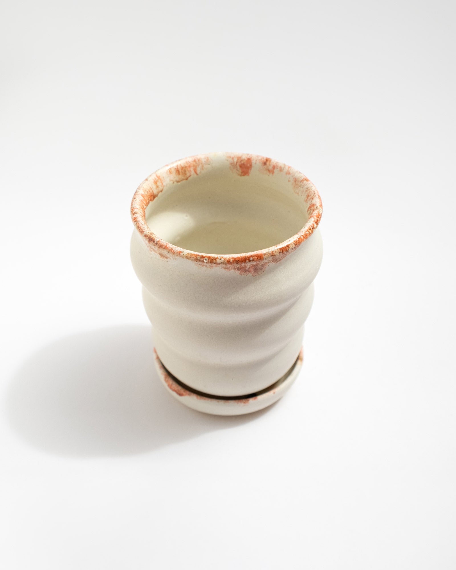 Handmade white stoneware planter with rust-red rim texture and raised foot for drainage